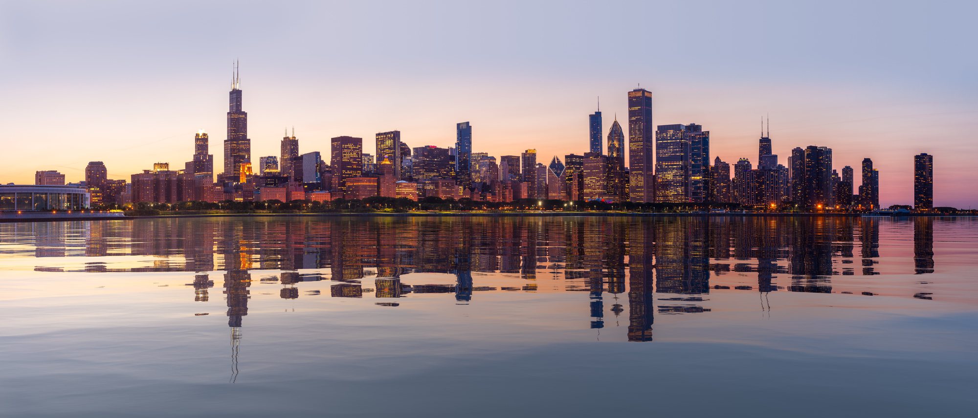 The Chicago skyline at sunrise, mirrored in the still water of Lake Michigan